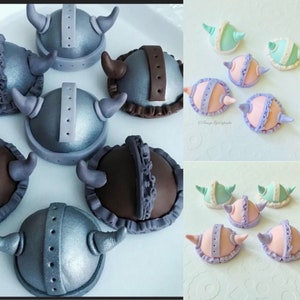 May include: Assortment of decorated cake toppers in various colors and designs. Some toppers are shaped like helmets, others are shaped like flowers. The toppers are made of fondant and are perfect for decorating cakes and cupcakes.
