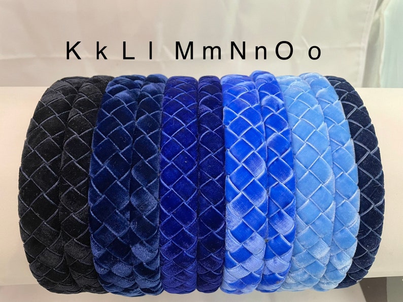 May include: Eight velvet headbands in various shades of blue, from dark navy to light blue, with a quilted pattern. The headbands are arranged in a row, with the darkest shade on the left and the lightest shade on the right. The text "KKLIMmNnOo" is written above the headbands.