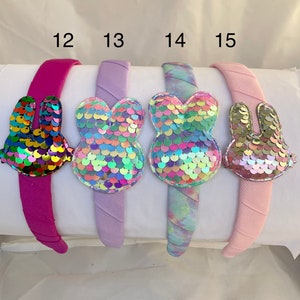 May include: Four headbands with different colors and designs. Each headband has a sequin bunny attached. The headbands are labeled 12, 13, 14, and 15.