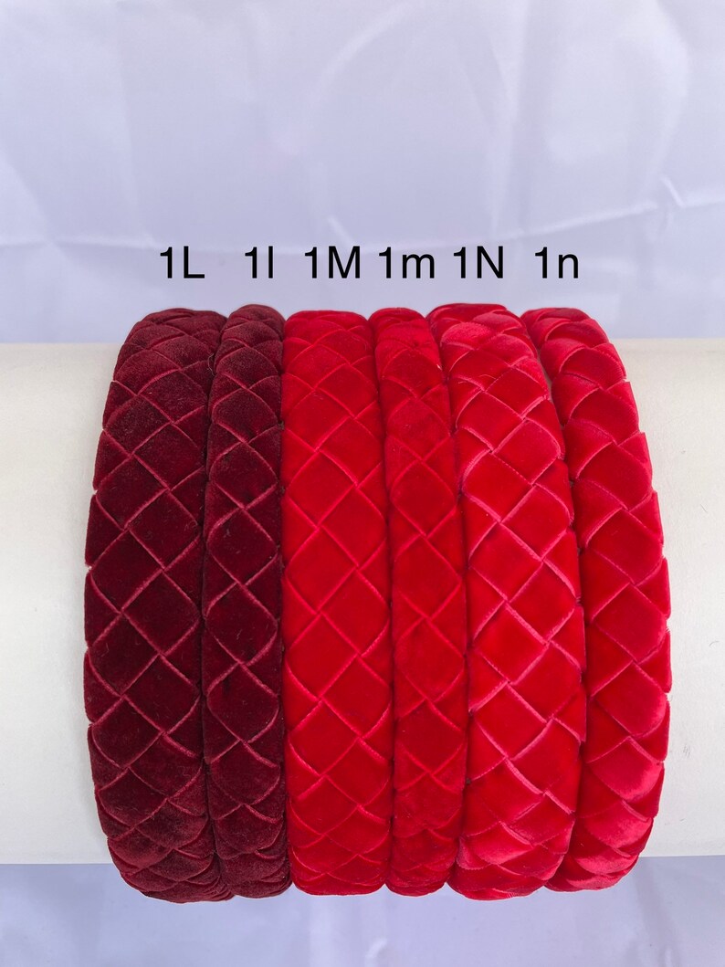 May include: Six velvet headbands in different shades of red, from burgundy to bright red. The headbands are all the same style, with a woven diamond pattern. The headbands are labeled 1L, 1I, 1M, 1m, 1N, and 1n.