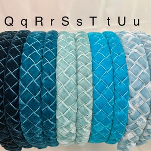 May include: Seven velvet headbands in various shades of blue, from dark blue to light blue. The headbands are all quilted with a diamond pattern. The headbands are labeled with the letters Q, q, R, r, S, s, T, t, U, u.