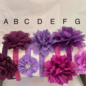 May include: Seven purple and lavender fabric flower headbands with different styles and textures. The headbands are labeled A through G.