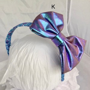 May include: A headband with a large iridescent purple bow. The headband is decorated with a blue and white pattern.