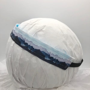May include: A blue and white headband with a watercolor mountain design. The headband is made of a soft, stretchy material and is perfect for keeping hair out of your face.