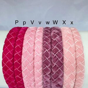 May include: Six velvet headbands in different shades of pink and red. The headbands are arranged in a row from left to right, with the darkest shade on the left and the lightest shade on the right. The headbands are all quilted with a diamond pattern.