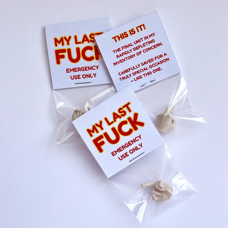 Op de afbeelding: Drie kleine plastic zakjes met elk een miniatuur handgebaar figuur. Elk zakje heeft een witte kaart met de tekst "MY LAST FUCK EMERGENCY USE ONLY" in rood en zwart. E&eacute;n kaart leest "THIS IS IT!" met extra tekst.
