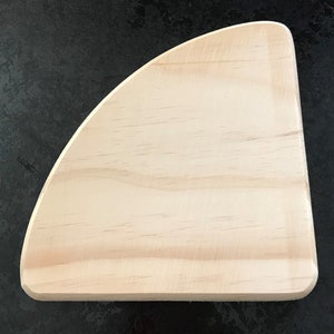 May include: A light wood shelf bracket with a curved edge. The bracket is unfinished and ready to be stained or painted.