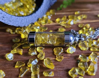 May include: A cylindrical glass pendant filled with small, translucent yellow crystal chips. The pendant features polished silver-tone metal caps on both ends and is attached to a silver-tone chain, surrounded by loose yellow crystal chips.