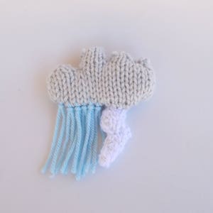 May include: A gray knitted cloud with blue yarn rain and a white knitted lightning bolt.