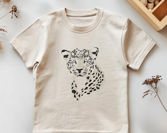 May include: A beige short-sleeved t-shirt with a black and white graphic of a leopard's face.