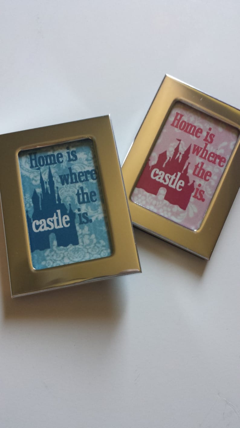 May include: Two silver framed pictures with a blue and pink background. The pictures feature a silhouette of a castle and the text "Home is where the castle is."