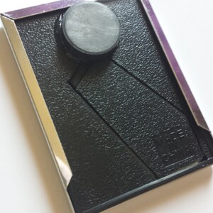 May include: A black picture frame with a silver border and a black magnet on the front. The frame has a textured surface and the text "WIRE CHAIN" is visible in the bottom right corner.