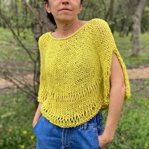 May include: A yellow knitted top with a loose fit and a slightly cropped length. The top has a round neckline and short sleeves.