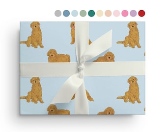 May include: Blue wrapping paper with a repeating pattern of golden doodle dogs. The paper is tied with a white ribbon.