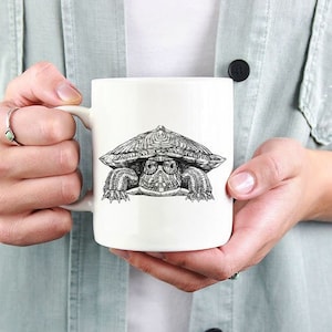 May include: White ceramic mug with a black and white illustration of a turtle wearing glasses and peeking out from behind a shell.