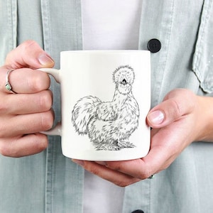 May include: White ceramic mug with a black and white line drawing of a Silkie chicken.