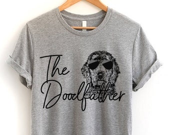 May include: A gray t-shirt with the text "The Doodlfather" in black script. A black and white illustration of a dog wearing sunglasses is above the text.