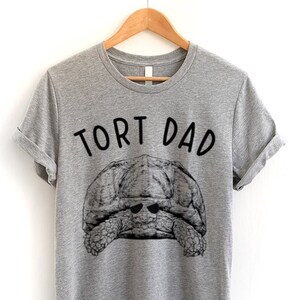 May include: Gray t-shirt with a black and white illustration of a turtle wearing sunglasses and the text "Tort Dad".