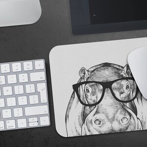 Peut inclure: Une illustration en noir et blanc d'un hippopotame portant des lunettes à monture noire. L'hippopotame est dessiné dans un style réaliste avec des détails précis.