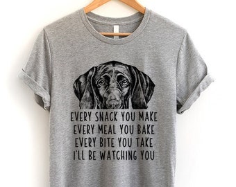 May include: Gray t-shirt with a black and white illustration of a dog's head and the text "EVERY SNACK YOU MAKE EVERY MEAL YOU BAKE EVERY BITE YOU TAKE I'LL BE WATCHING YOU"