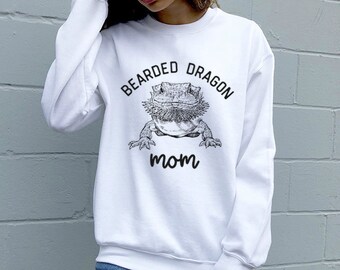 May include: White sweatshirt with a black and white illustration of a bearded dragon and the text "Bearded Dragon Mom".