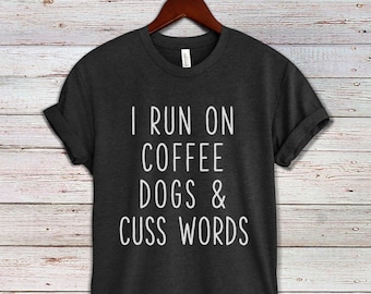 May include: A dark gray t-shirt with the text "I run on coffee dogs & cuss words" printed in white.