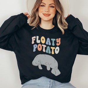 May include: A black sweatshirt with the text "FLOATY POTATO" in rainbow colours and a cartoon manatee illustration.