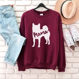 May include: A maroon sweatshirt with a white silhouette of a dog and the word "Mama" printed on the front.