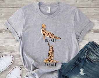 May include: A gray t-shirt with a graphic of a cat in a yoga pose. The text "inhale" and "exhale" are printed below the cat images.