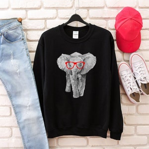 May include: Black sweatshirt with a gray elephant wearing red glasses. The elephant is centered on the sweatshirt.