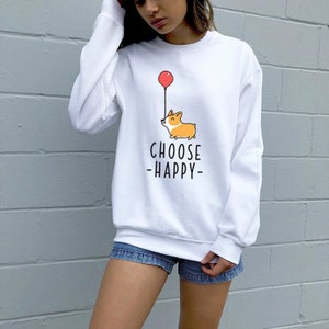 May include: White sweatshirt with a cartoon corgi holding a red balloon. The text "CHOOSE -HAPPY- " is printed below the corgi.