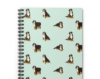 May include: A spiral bound notebook with a light green cover featuring a repeating pattern of Bernese Mountain Dogs. The dogs are brown, black, and white.