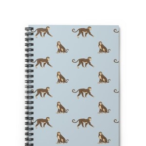 May include: A light blue spiral notebook with a repeating pattern of brown monkeys. The monkeys are in various poses, some walking, some sitting, and some looking to the side.