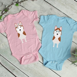 May include: Two baby onesies, one pink and one blue, with a cartoon husky dog graphic. The pink onesie has a flower crown on the dog, and the blue onesie has glasses on the dog.