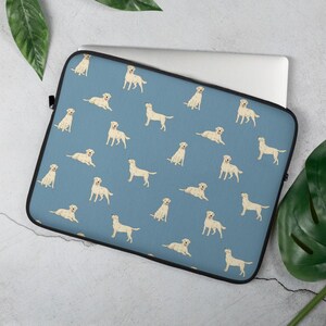 May include: A blue laptop sleeve with a repeating pattern of white Labrador Retriever dogs. The dogs are in various poses, including sitting, standing, and lying down.