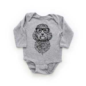 May include: A gray long-sleeved baby onesie with a black and white illustration of a poodle wearing glasses.