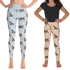 May include: Two pairs of leggings featuring a monkey print. One pair is light blue with brown monkeys, the other is light brown with brown monkeys.