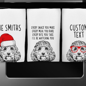May include: Three kitchen towels with a doodle of a dog wearing different accessories. The first towel says "THE SMITHS" and the dog is wearing a Santa hat. The second towel says "EVERY SNACK YOU MAKE EVERY MEAL YOU BAKE EVERY BITE YOU TAKE I'LL BE WATCHING YOU". The third towel says "CUSTOM TEXT" and the dog is wearing red glasses.