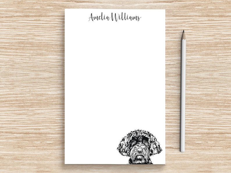 K&ouml;nnte beinhalten: Wei&szlig;er Notizblock mit schwarzer Tinte, der Name "Amelia Williams" oben und eine Schwarzwei&szlig;illustration eines Hundekopfes, der unten herausguckt.