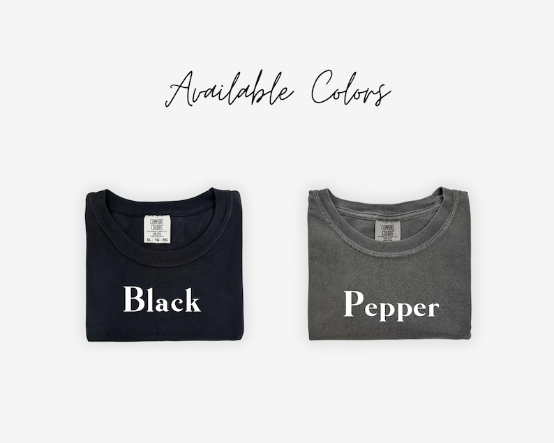 May include: Two folded t-shirts, one black and one pepper-colored, are displayed against a white background. The text "Available Colors" is written in cursive at the top. The black shirt has the word "Black" printed on it, and the pepper shirt has the word "Pepper".