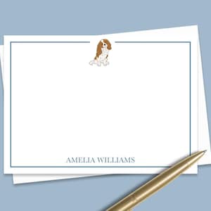 May include: White stationery with a blue border and a small illustration of a brown and white Cavalier King Charles Spaniel. The text "AMELIA WILLIAMS" is printed at the bottom.