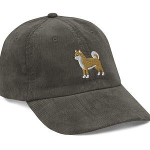 May include: A dark green corduroy baseball cap with an embroidered Shiba Inu dog on the front.
