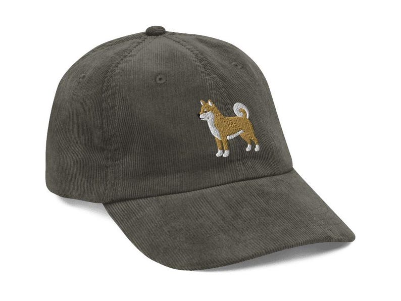 May include: A dark green corduroy baseball cap with an embroidered Shiba Inu dog on the front.
