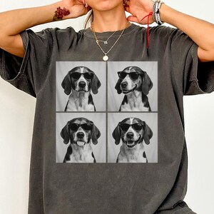 May include: Dark grey t-shirt with a four-panel image of a beagle wearing sunglasses. The beagle's expressions vary in each panel. The shirt has a relaxed fit, suitable for casual wear. The t-shirt is a comfortable fit.