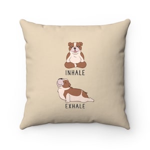 May include: Beige throw pillow with a cartoon bulldog in a yoga pose. The text "INHALE" and "EXHALE" are printed below the bulldogs.