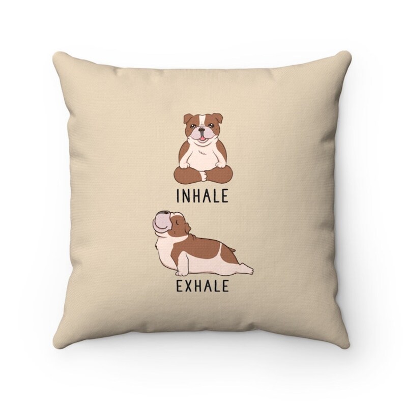 May include: Beige throw pillow with a cartoon bulldog in a yoga pose. The text "INHALE" and "EXHALE" are printed below the bulldogs.