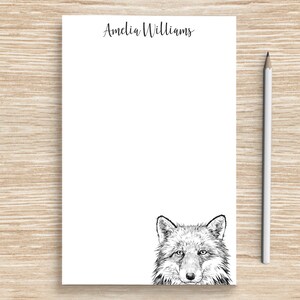 May include: White notepad with the name "Amelia Williams" printed at the top. A black and white illustration of a wolf's face is at the bottom of the notepad.