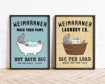 May include: Two framed prints with a vintage aesthetic. One features a Weimaraner in a bathtub with the text "Wash Your Paws" and "Hot Bath 25¢". The other shows a Weimaraner in a laundry basket with the text "Laundry Co." and "25¢ Per Load".