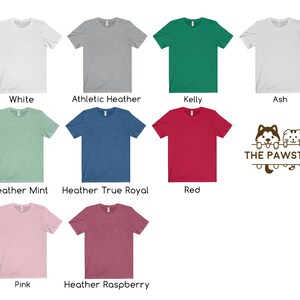 May include: A variety of t-shirt colors, including white, heather grey, kelly green, ash, heather mint, heather true royal, red, pink, and heather raspberry. The t-shirts are all crew neck and short sleeve. The image also includes a logo with the text "THE PAWSTER" and a cartoon image of a husky and a cat.