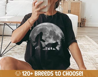 May include: Black t-shirt featuring a graphic of Bigfoot walking a dog in front of a full moon. The text "120+ BREEDS TO CHOOSE!" is at the bottom of the image.
